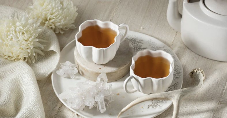 Dos tazas de té en porcelana blanca sobre un plato de encaje